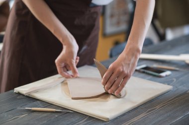 Kadınların parmakları gelecekteki seramik bir ürünün kil parçasını ekleyip ayarlıyor.