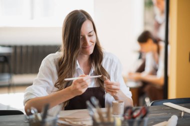 Sanat atölyesindeki atölyede ders sırasında kille heykel yapmayı öğrenen genç kadınlar.