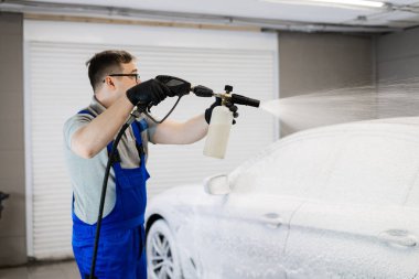 Araba yıkamada otomobili köpükle kaplayan işçi.