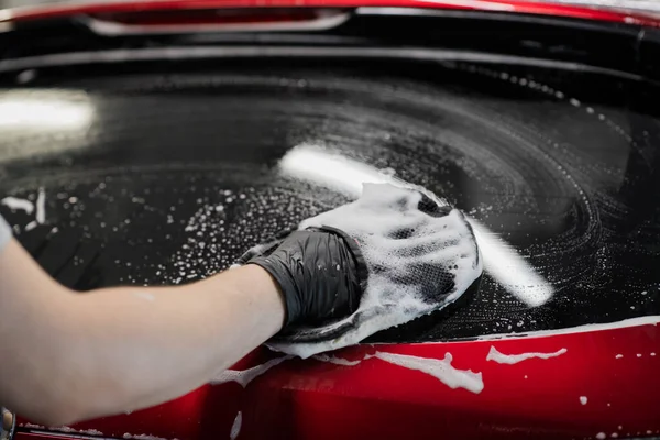 Detallado del coche - el hombre lava el coche con una mano cubierta con un guante de lavado especial, primer plano. — Foto de Stock