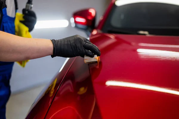 Detailní záběr muž nanášení keramického povlaku na červené auto na detailní servis. — Stock fotografie