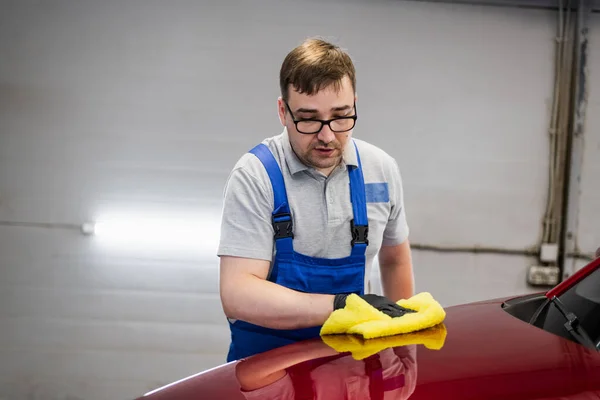 El hombre limpia la superficie del coche de gotas usando limpiaparabrisas. — Foto de Stock