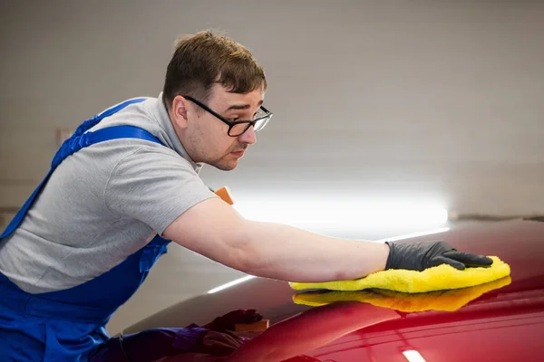 Hombre pulido coche de limpieza con tela de microfibra, detalle o valeting concepto. Lavado profesional limpiando el capó del coche. — Foto de Stock