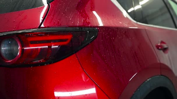 Detailní záběr odfoukává vodu z čerstvě umytého červeného auta vzduchem. Mytí aut a detailní servis. — Stock video