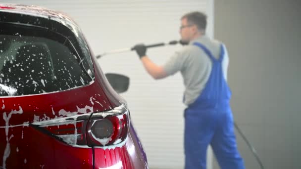 Araba yıkama köpüklü ve yüksek basınçlı suyla. Araba yıkama ve temizlik servisinde kırmızı araba.. — Stok video