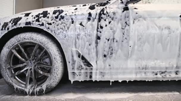 Liquido schiumoso caduta della cappa auto. Vista su un lato di un'auto all'atto di autolavaggio. — Video Stock
