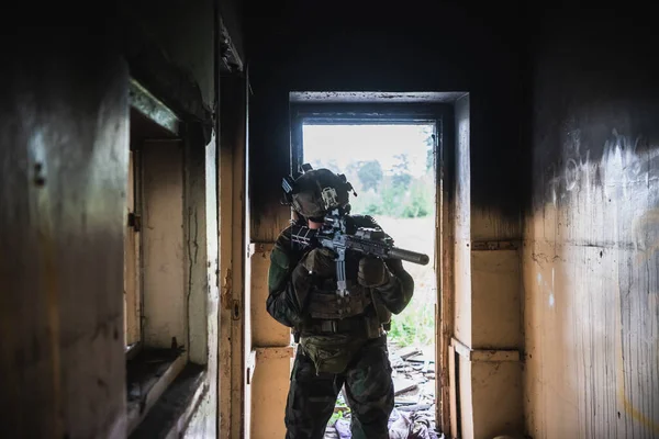 身着全套美国MARSOC装备的士兵进入废弃建筑，用MK18突击步枪瞄准不同角度 — 图库照片