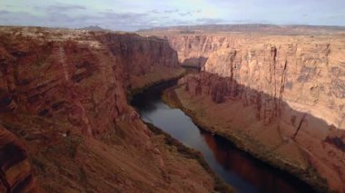 Glen Canyon Barajı, Arizona, ABD yakınlarındaki dikey kırmızı kumtaşı uçurum duvarlı derin kırmızı kanyonda 4K uçuş..