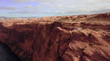 İnsansız hava aracı, el sallayan iki turistin yanından geçiyor. Glen Canyon barajı ve Arizona, ABD 'deki Powell Gölü yakınlarındaki uçurumun kenarında duruyorlar..