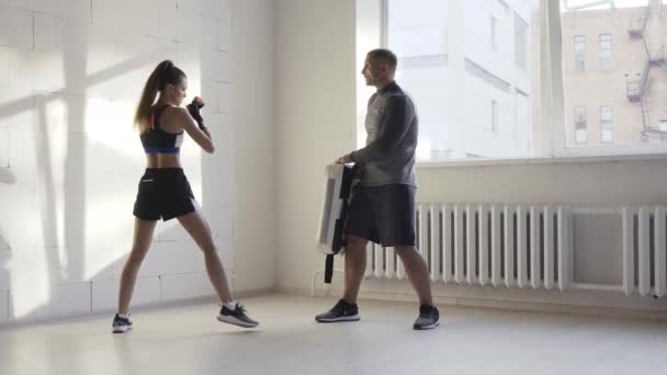 Female martial arts fighter practicing with trainer, punching taekwondo kick pad exercise kicking. Training of kickboxer woman strikes with bare foot mitts punching bag kicking shield — Stock Video