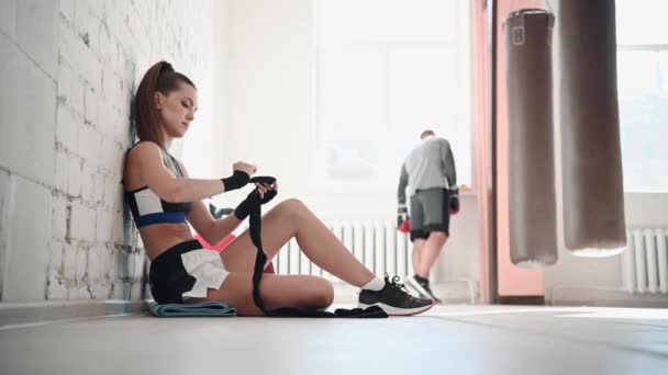 Mulher boxeadora se prepara para uma luta rolando ligaduras em seus punhos. Boxe feminino. — Vídeo de Stock