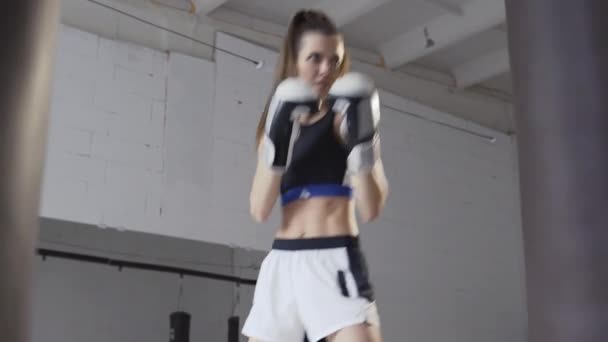 Atleta femenina boxeando el saco de boxeo en gimnasio industrial urbano — Vídeos de Stock