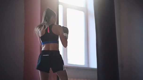 Bojovnice trénuje jeho údery, tréninkový den v boxerské tělocvičně, dívka trénuje sérii úderů — Stock video