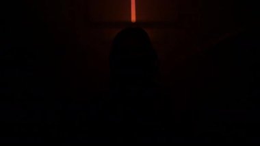 Şehrin karanlık yeraltı tünelinin kırmızı ışıklarında koruyucu yüz maskesi takan kadın kameraya bakıyor. Covid-19 salgını - depresyon ve üzüntü.