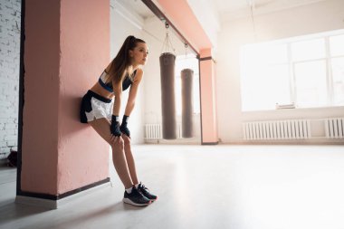 Kadın dövüşçü susuzluktan bitkin düştü. Genç bir kadın bir boks stüdyosunda yoğun bir eğitimden sonra dinleniyor..