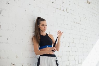 Genç ve güzel bir sporcu antrenmandan önce koluna bir boks bandajı sarar.