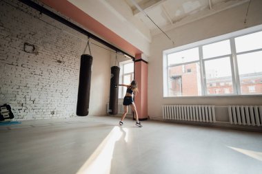Güzel kickboks kadını spor salonunda çantayla antrenman yapıyor..