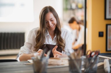 Esnaf kadın çömlekçi çömlekleri için malzeme hazırlıyor. Kadın elleri gelecekteki seramik ürünlere kilden parçalar ekliyor. Yakın plan çalış..