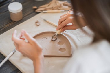 Usta bir çömlekçinin yakın çekimi, kil kesme özel bir alet. Dişi sanatçı tahta bir döngü aracıyla kesiyor