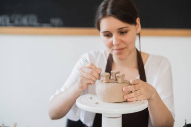 Kadın eli değneği tutuyor ve dekoratif ürünlerle süs eşyası yapıyor. Çömlek ve seramik atölyesinde kil şekillendirme ustası.