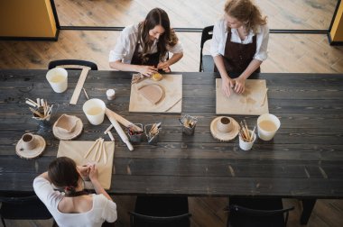 Sanat atölyesindeki atölyede ders sırasında kille heykel yapmayı öğrenen genç kadınlar.