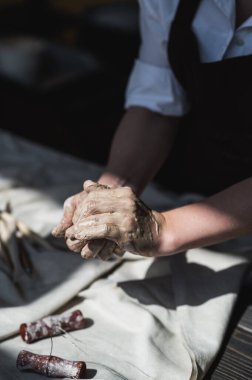 Çamur topu. Kadın ellerinin yakın çekimi çamurdan bir topu yoğurur ve tekerlek üzerinde çalışmaya başlar..