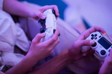 Evde video oyunu oynayan gülümseyen bir çift. Gençlerin salgın sırasında birlikte zaman geçirdikleri düşük açılı çekim..