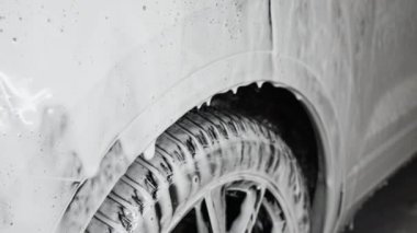 Araba kaputunun köpüklü sıvısı düşüyor. Oto yıkama yerindeki arabanın yanına bak..