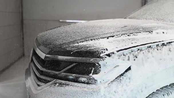 用雪白泡沫洗发水清洗汽车。把白色的雪沫喷在车篷和前灯上.把洗发水喷到车盖上 — 图库视频影像