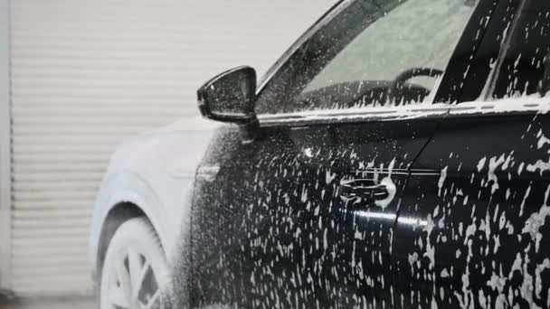 洗车过程。发泡的洗涤剂盖住车的侧面，把它从灰尘中清理干净. — 图库视频影像