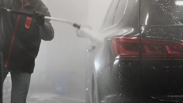 Faire laver les arcs de voiture noir travailleur sous l'eau à haute pression après l'application de mousse. Concept : Service de voiture automobile, Lavage de voiture, Machines de nettoyage. — Video