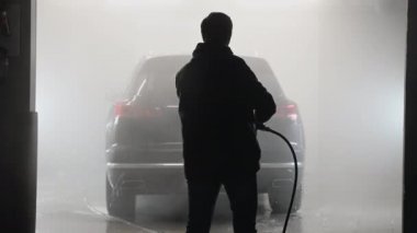 Araba yıkama ve temizlik. Profesyonel bir işçi araba yıkama makinesinde siyah bir arabayı yıkıyor..