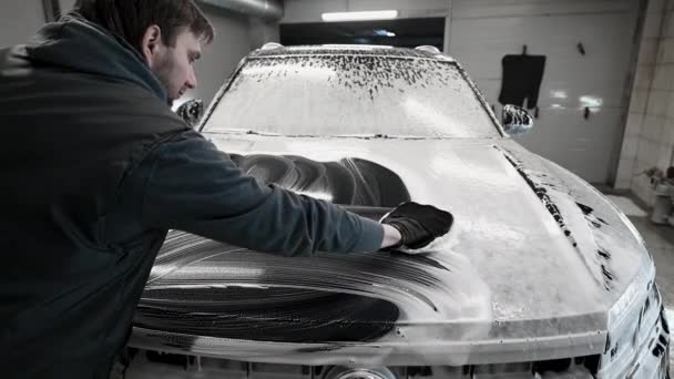 Mann wäscht Auto zurück, nachdem er die Karosserie mit einem speziellen Reinigungshandschuh gewaschen hat. — Stockvideo