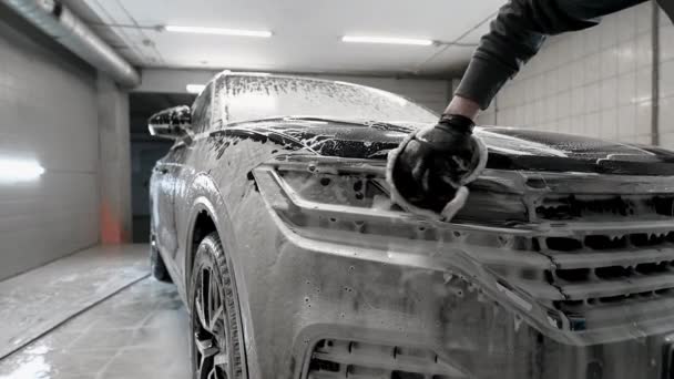 Detail auta - muž myje reflektory auta rukou pokrytou speciální prací rukavicí, zblízka. — Stock video