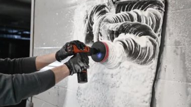 Otomobil temizliğinin ayrıntıları. Erkek, araba paspaslarını temizlemek için profesyonel kimyasal çözümler ve yörünge temizleyici kullanıyor..