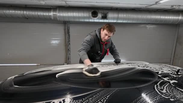 Man worker washing automotive on a car wash with black glove. — Stockvideo