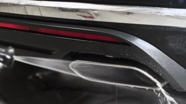 Yüksek basınçlı su jeti ile sabun deterjanıyla kaplı egzoz borusunu yıkayan adam..