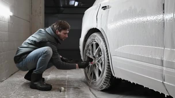 Car service: The worker washes car rims with a soft brush with shampoo — Stock Video