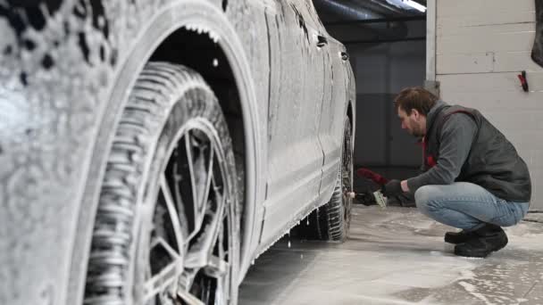Servicio de coches: El trabajador lava las llantas del coche con un cepillo suave con champú — Vídeos de Stock