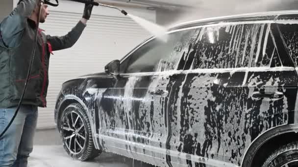 Trabajador en la tienda de lavado de coches, el uso de la lavadora de presión en el coche, el hombre lavando el coche con agua de compresión. — Vídeos de Stock