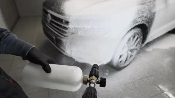 Mann deckt Auto mit Hochdruckreiniger mit Schaum ab Autowäsche. Ich-Perspektive. — Stockvideo
