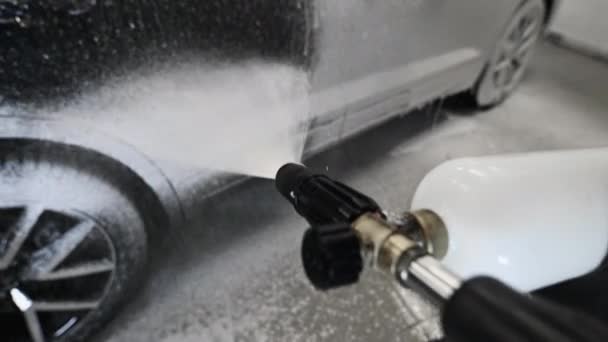 Auto met staande in car wash service. POV: bedek de auto met schuim met hogedruksproeier. — Stockvideo