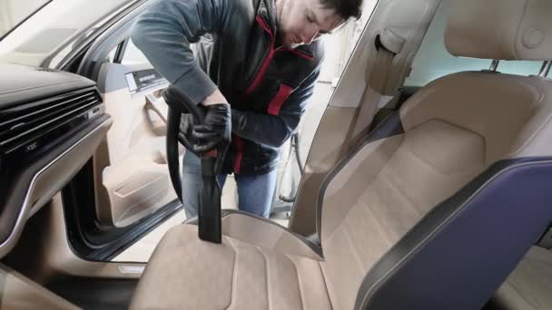 Mann reinigt den Vordersitz eines Autos mit Staubsauger. Innenreinigung und Detaillierung in der Waschanlage. — Stockvideo