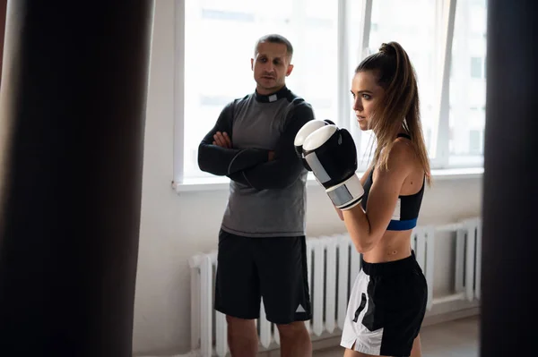 개인 트레이너와 복싱을 하는 여성. 여자 권투 선수에게 싸움 연습을 가르치는 강사 — 스톡 사진