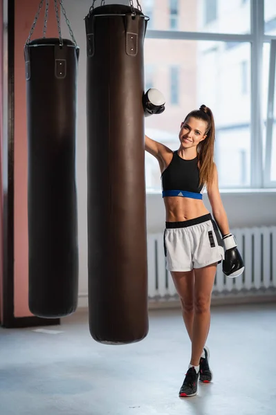 Atleta femenina boxeando el saco de boxeo en gimnasio industrial urbano — Foto de Stock