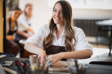 Sanat atölyesindeki atölyede ders sırasında kille heykel yapmayı öğrenen genç kadınlar.