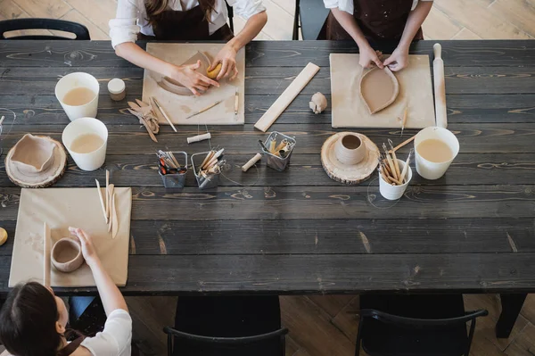 Mujeres jóvenes aprendiendo a esculpir con arcilla durante una lección en un taller en un estudio de arte. — Foto de Stock