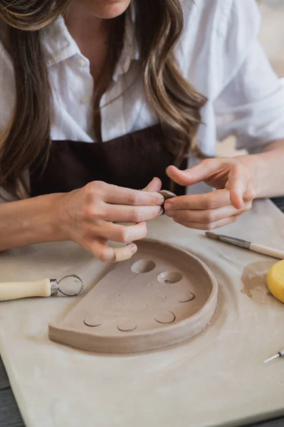 Καλλιτεχνική γυναίκα αγγειοπλάστη ετοιμάζει υλικό για την κεραμική της. Γυναικεία χέρια αποδίδουν μέρος πηλό στο μελλοντικό κεραμικό προϊόν. Κοντινό πλάνο εργασίας. — Φωτογραφία Αρχείου