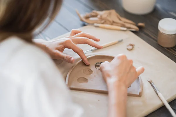 Жінка, що прикрашає керамічну тарілку ручної роботи крупним планом — стокове фото
