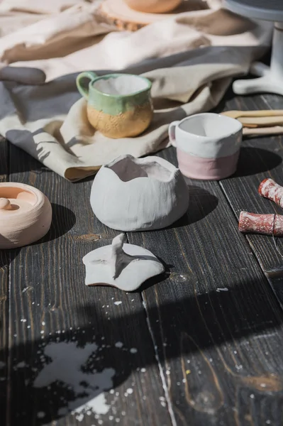 Une vue rapprochée des plaques d'argile et un pinceau sur une table en bois et des fleurs séchées sur un fond. Vaisselle artisanale dans un atelier de poterie. Céramique artisanale. Concept de studio de poterie. — Photo